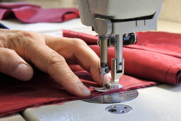 Портной с помощью швейной машинки для сшивания тканей
