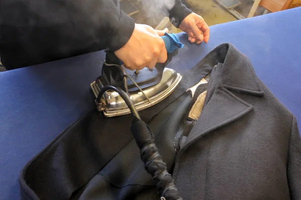 Hands of professional tailor ironing textile with steaming — Stock Photo, Image