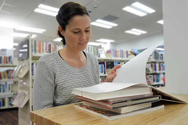 Estudante do sexo feminino lendo um livro em uma biblioteca — Fotografia de Stock