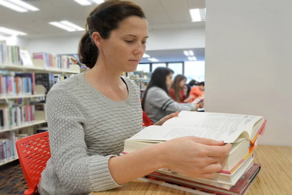 Kvinnlig student forskar böcker i ett bibliotek — Stockfoto