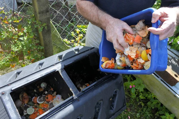 Manos vaciando un contenedor lleno de desperdicios domésticos de alimentos — Foto de Stock