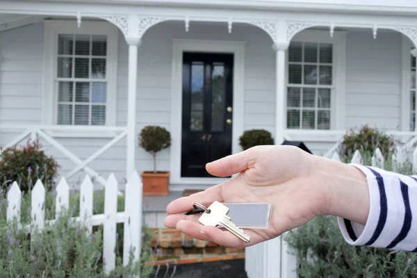 Mão das mulheres segura uma chave contra uma casa em Auckland Nova Zelândia — Fotografia de Stock