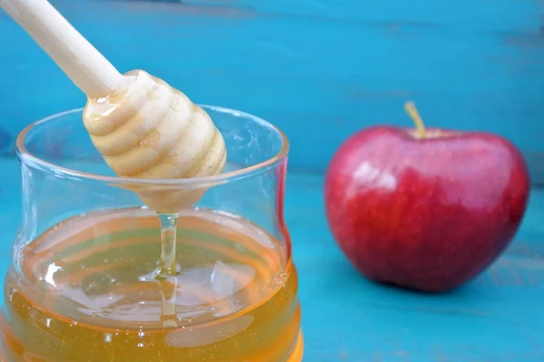 Tarro de miel y manzana roja sobre fondo turquesa — Foto de Stock