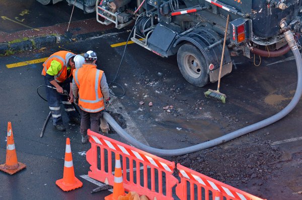 Road workers cleaning sewage in city street