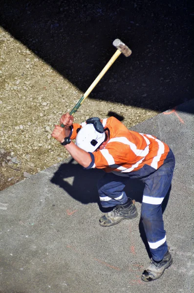 Straßenarbeiter hält schweren Hammer in der Hand und schlägt zu — Stockfoto