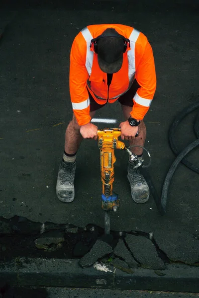 Trabalhador rodoviário com uma broca quebrando asfalto na estrada — Fotografia de Stock