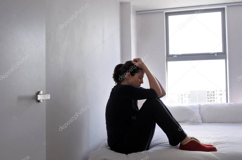 Depressed adult victim woman sitting and crying on bed