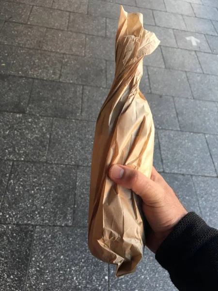 Homem carrega uma garrafa de álcool em um saco de papel — Fotografia de Stock