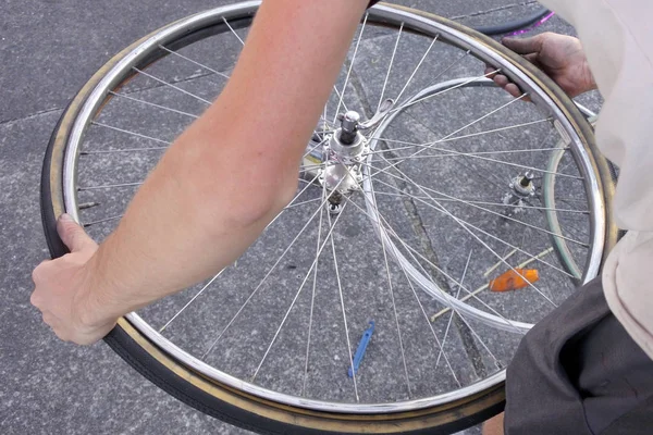 Mains d'un homme fixant une roue plate — Photo