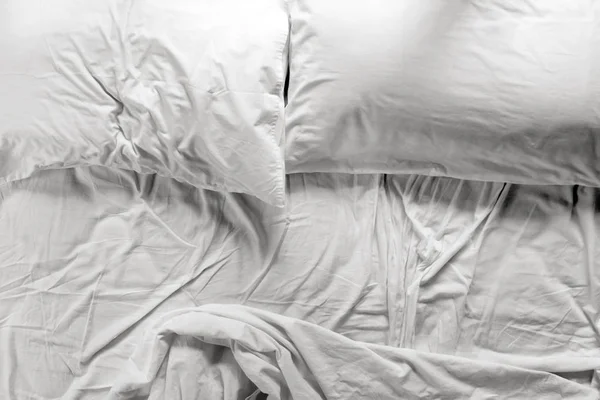 Unmade bed in a bedroom with two pillows and crumpled bed sheet — Stock Photo, Image