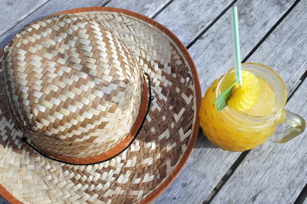 Sombrero de paja con bebida de cóctel amarillo servido en una mesa en un tro —  Fotos de Stock