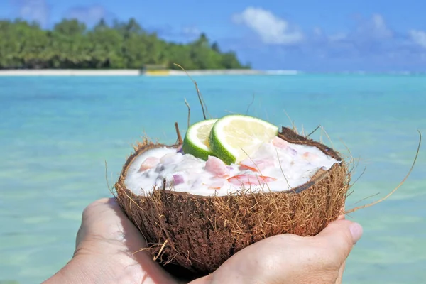Frau hält Ceviche-Gericht, das in einer Kokosnussschale serviert wird, gegen eine Insel — Stockfoto