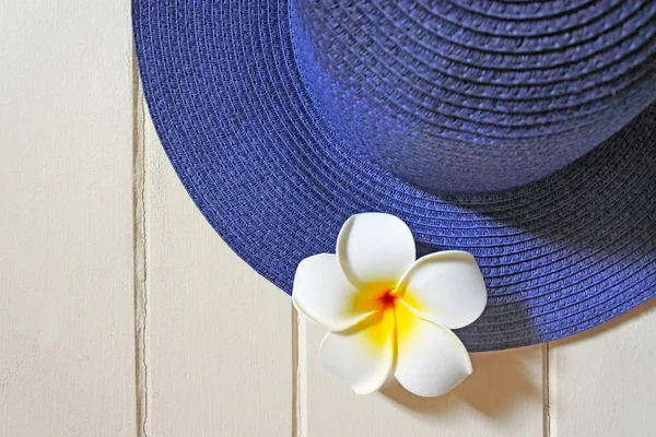 Chapéu feminino azul com flor Plumeria branca em uma superfície de madeira — Fotografia de Stock