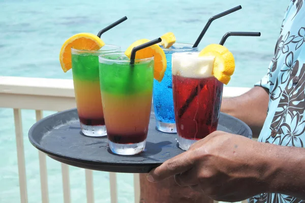 Pacific islander male waiter serving cocktails on a tropical pac