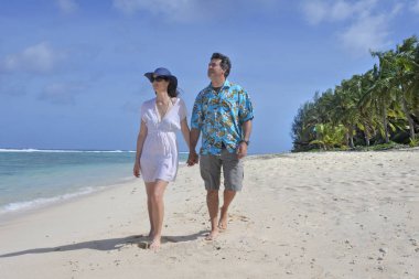 Honeymoon couple walks on a tropical pacific island beach in Rar clipart