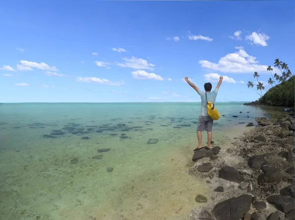 Young man with winner hands up stands on islet in Muri  lagoon i — Stock Photo, Image