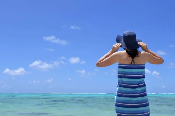 Vrouw dragen zon hoed en verpakt in een strandlaken staat op roc — Stockfoto