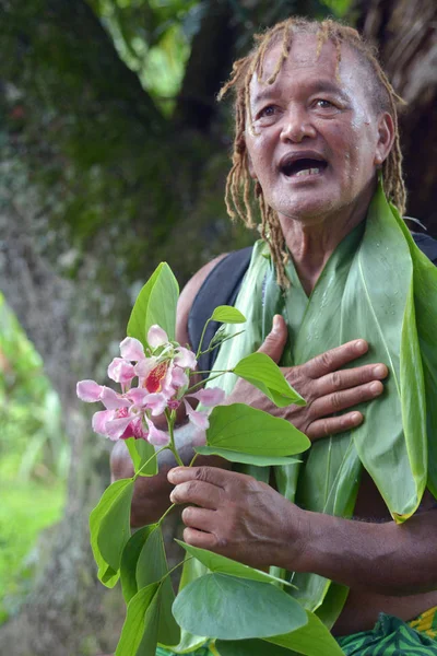 Olde aged Pacific Islander man explains about exotic flower on e — Stock Photo, Image