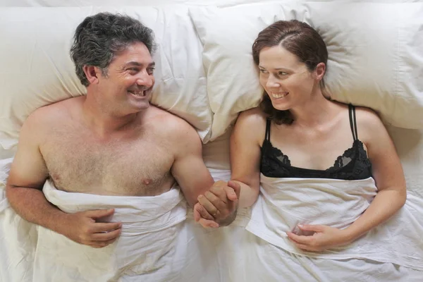 幸せな男と女のビューの上部手をつないでベッドに横たわっていた — ストック写真