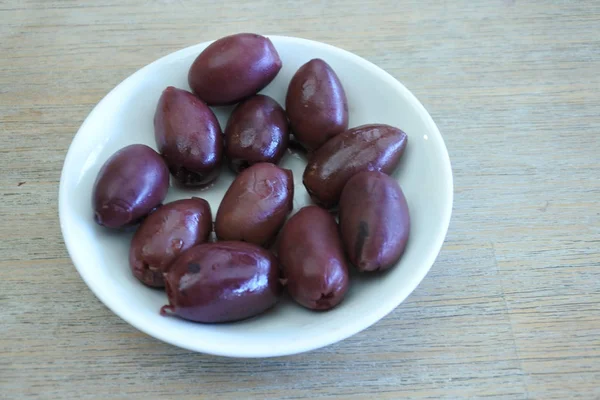 Kalamata-Oliven in einem Teller auf einem Holztisch serviert — Stockfoto