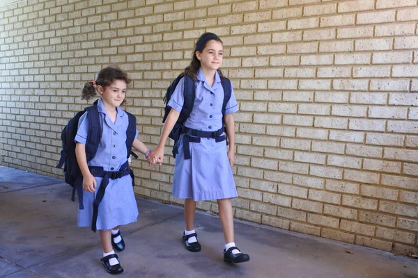 Duas irmãs estão de mãos dadas indo para a escola juntas — Fotografia de Stock