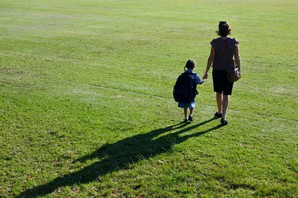 Вид ззаду мати і дочка йдуть разом до школи — стокове фото