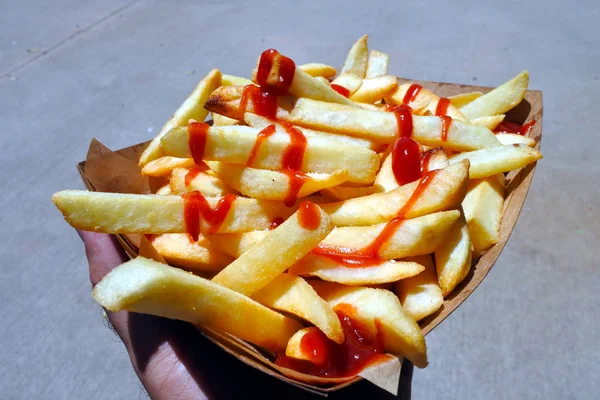 Hombre mano sosteniendo papas fritas frescas con salsa de tomate listo para e — Foto de Stock