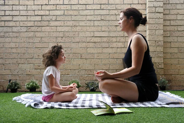 Mãe e filha jovem meditando juntos no jardim em casa — Fotografia de Stock