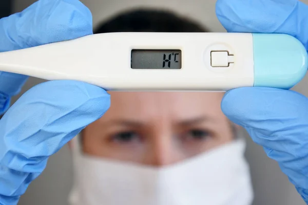 Medical person wearing medical face mask measuring temperature to a sick person with very high temperature on body thermometer. Real people. Copy space