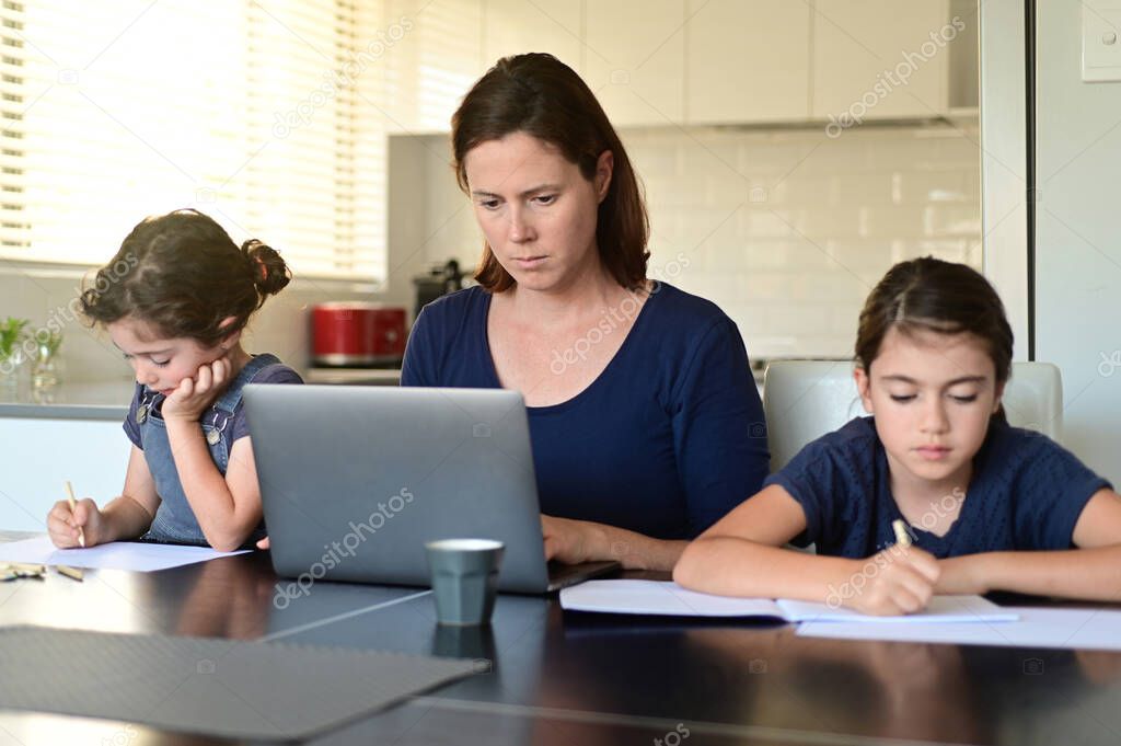Single mother and daughters at home as the pandemic coronavirus (COVID-19) forces many employees and students to work and study from home. Real people. Copy space