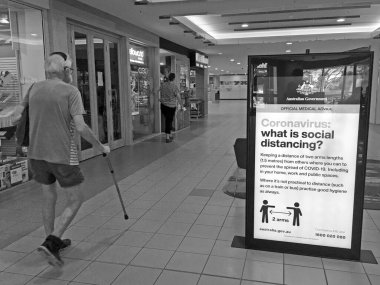 PERTH - MAR 24 2020: Avustralya Sağlık Bakanlığı 'nın önünden geçen Avustralyalılar, bulaşıcı bir hastalığın yayılmasını durdurmak veya yavaşlatmak amacıyla alışveriş merkezindeki Sosyal Mesafe Kılavuzu posterleri.