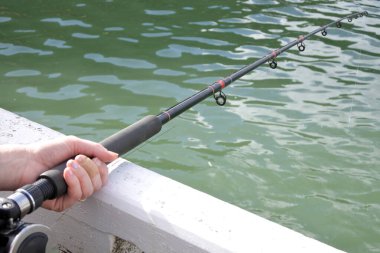 İskeleden olta tutan kadın elleri. İnsan yok. Boşluğu kopyala