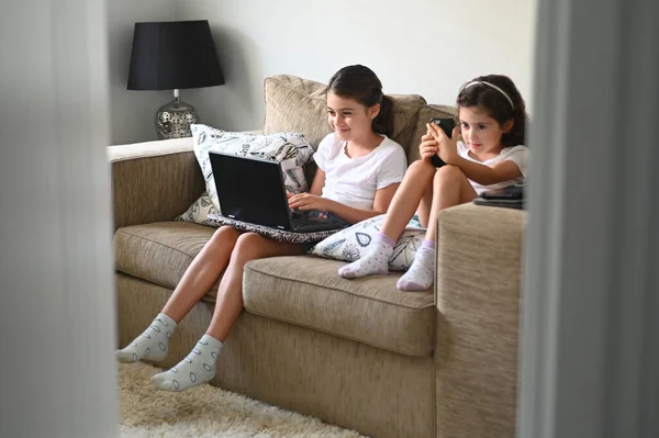 Dvě Sestry Věku Let Sedí Gauči Používají Mobilní Zařízení Během — Stock fotografie
