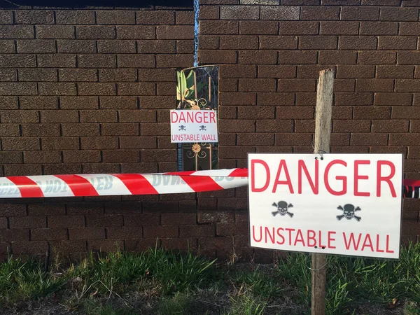 Danger unstable wall sign beside a boundary wall.