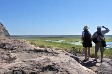 Avustralyalı turist çift Ubirr Kayası 'nda yürüyüş yaparken Avustralya' nın kuzeyindeki Kakadu Ulusal Parkı manzarasına bakıyor..