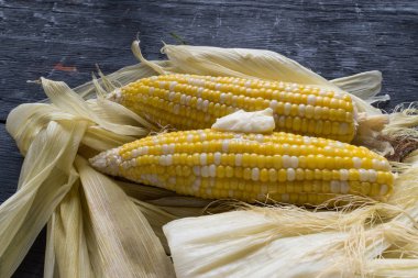 eritilmiş tereyağı ile koyu arka plan üzerinde shucked sarı mısır