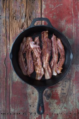 domuz pastırması şeritler dökme demir tavada yukarıdan aşağı görünüme rustik ahşap tablo