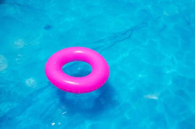 Parlak pembe oyuncak yüzük şişme parlak mavi su ile Yüzme havuzunda