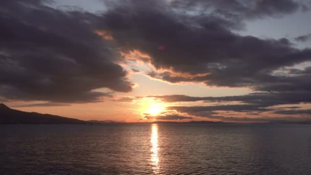 它显示毛茸茸的云彩缓缓向夕阳西下移动 太阳的金黄色光芒反射在完全平静的海洋中 — 图库视频影像