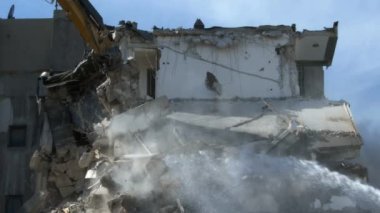 Hidrolik şalter ve sütun kesici kazıcı arka makine eski apartman binalarının yıkımında çalışıyor. Ekskavatör inşaat alanını yıkıyor..