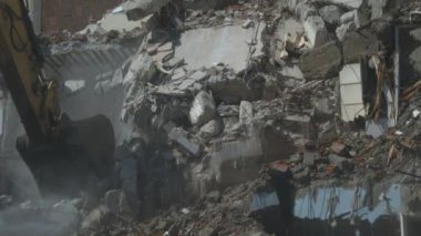 Hidrolik şalter ve sütun kesici kazıcı arka makine eski apartman binalarının yıkımında çalışıyor. Ekskavatör inşaat alanını yıkıyor..