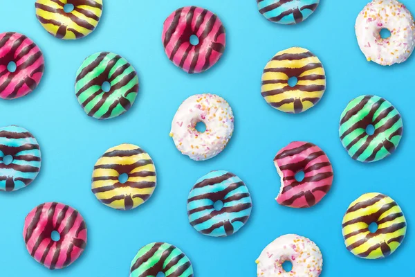 Set of donuts with pink, yellow, blue and white glaze and various toppings on blue background. Poster
