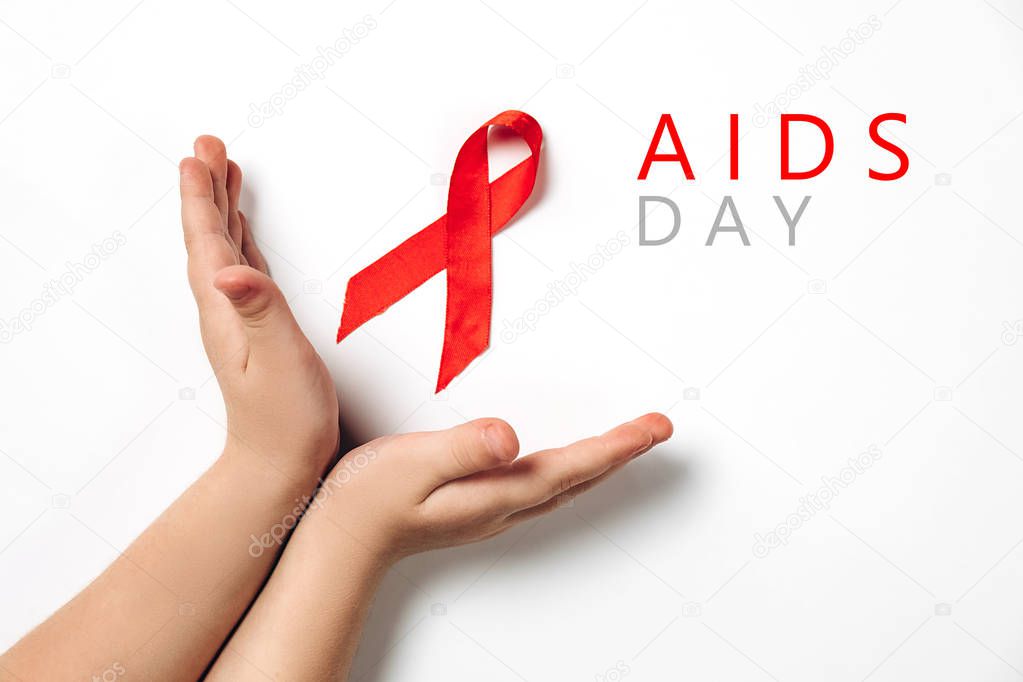 Close up horizontal image of child's hands holding red ribbon on