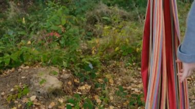 Genç, tatlı esmer kadın, hamakta asılı, mutlu gülümsüyor, bağımsız yaşam tarzından zevk alıyor, sonbahar günü gri kazak ve şapka giyiyor, ağır çekimde. İnsanların rahatlama seyahat konsepti