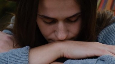 İyimser Avrupalı kadın portresi kendini özgür ve mutlu hissediyor. Hamakta uzanmış, mutlu bir şekilde gülümsüyor, bağımsız yaşam tarzının tadını çıkarıyor. Gri kazak ve şapka giymiş, ağır çekim.