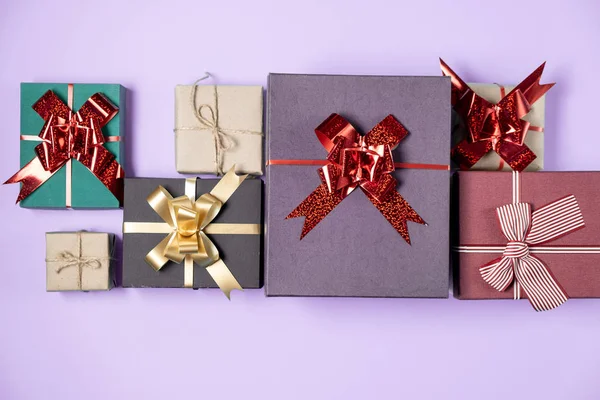 Composición festiva. Varias cajas de regalo hechas a mano sobre fondo violeta pastel. Concepto de cumpleaños. Plano, vista superior, espacio para copiar —  Fotos de Stock