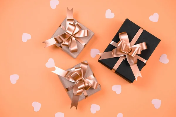 Vakantie achtergrond. Diverse handgemaakte geschenkdozen versierd met roze hart confetti op oranje achtergrond. Minimale stijl en Valentijnsdag concept. Vlakke lay, bovenaanzicht, kopieerruimte — Stockfoto