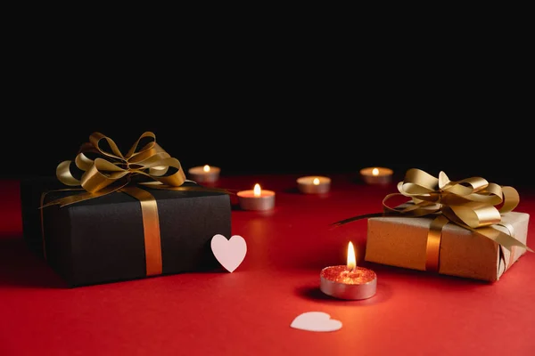 Fondo del Día de San Valentín. Varias cajas de regalo hechas a mano decoradas con confeti corazón rosa, vela sobre fondo rojo y negro. Estilo mínimo y concepto de día de San Valentín. Colocación plana, espacio de copia — Foto de Stock