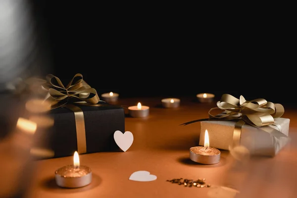 Fondo de vacaciones. Varias cajas de regalo hechas a mano decoradas con confeti corazón rosa, vela sobre fondo naranja y negro. Estilo mínimo y concepto de día de San Valentín. Colocación plana, espacio de copia — Foto de Stock