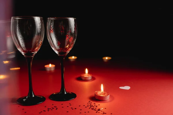 Valentijnsdag achtergrond. Twee klappende wijnglazen, confetti, kaars op rode en zwarte achtergrond. Minimale stijl en Valentijnsdag concept. Vlakke lay, kopieerruimte — Stockfoto